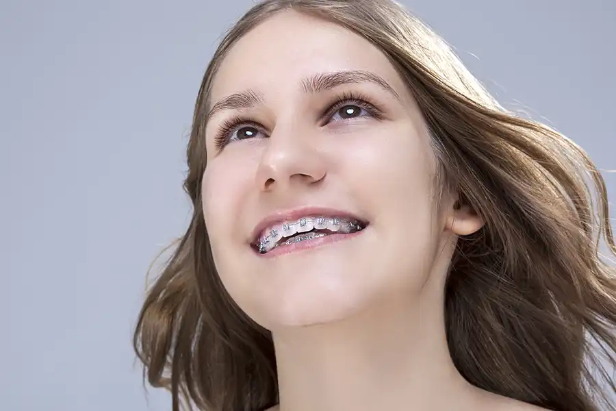 Close-up of a young girl with braces smiling broadly.