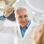 Dental professional holding light over woman in dentist chair