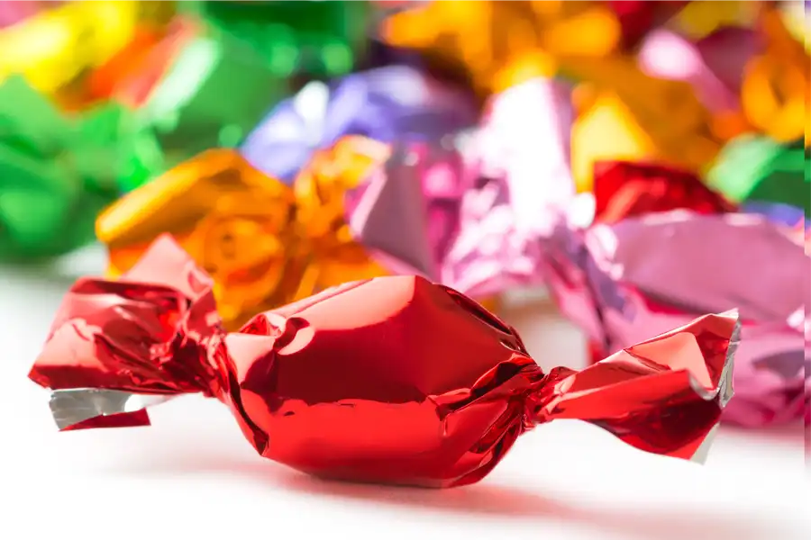 A red candy in the foreground with other colored candies behind it