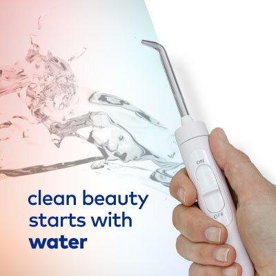 Clean Beauty - water with hand holding Waterpik water flosser handle