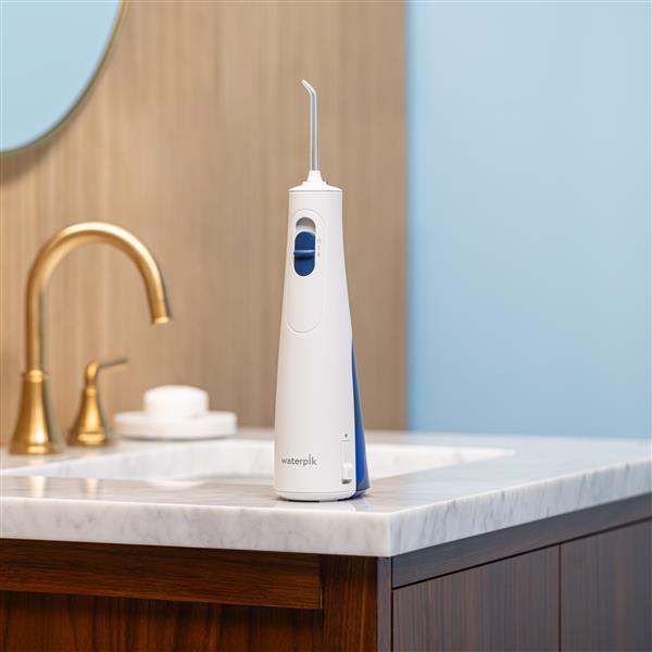 White Cordless 1200 handheld water flosser on a bathroom sink.