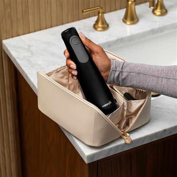 Black Cordless Enhance 3200 handheld water flosser, without tip, taken out of a toiletry bag.