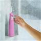 Mauve Cordless Pulse 3100 water flosser on a shower ledge, with a hand reaching for it.