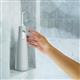 Gray Cordless water flosser on a shower ledge, with a hand reaching for it.