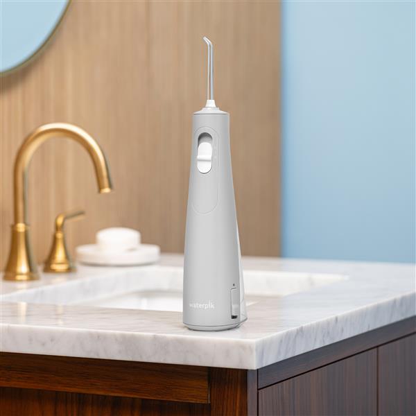 Gray Cordless handheld water flosser on a bathroom sink.