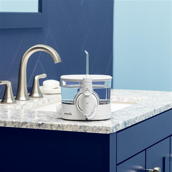 White ION countertop water flosser on a bathroom sink.