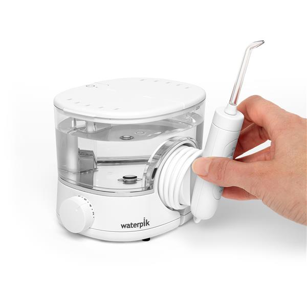 White ION countertop water flosser, with hand holding the handle and attached tip to place in magnetic handle cradle.
