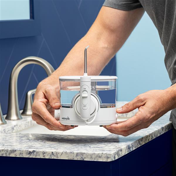 White ION countertop water flosser held in hands for scale, moving it.