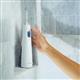 White Cordless 1000 water flosser on a shower ledge, with a hand reaching for it.