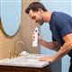 White Cordless 1200 handheld water flosser in use, with person leaning over the bathroom sink.