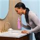 Mauve Cordless Pulse 3100 handheld water flosser in use, with person leaning over the bathroom sink.