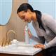 Gray Cordless handheld water flosser in use, with person leaning over the bathroom sink.