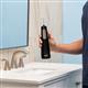 Black Cordless Enhance 3200 handheld water flosser held vertically above bathroom sink.