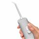 Gray Cordless handheld water flosser held vertically above bathroom sink.
