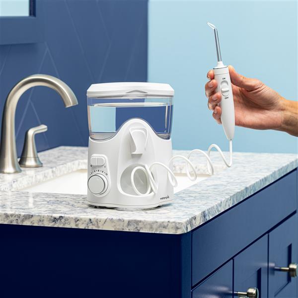 Hand holding handle of Ultra Plus water flosser on bathroom counter